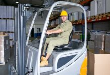 Frota mista: combinar empilhadeiras alugadas e próprias pode beneficiar a operação; entenda trabalhador-de-logistica-masculino-positivo-no-capacete-de-seguranca-dirigindo-uma-empilhadeira-no-armazem-sorrindo-olhando-para-longe