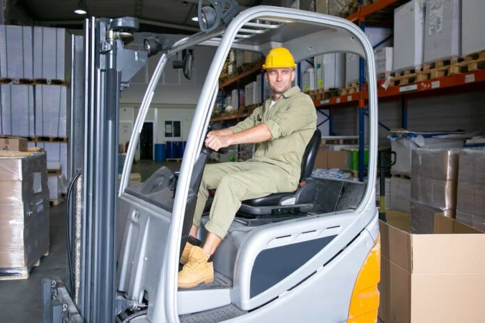 trabalhador-de-logistica-masculino-positivo-no-capacete-de-seguranca-dirigindo-uma-empilhadeira-no-armazem-sorrindo-olhando-para-longe2 trabalhador-de-logistica-masculino-positivo-no-capacete-de-seguranca-dirigindo-uma-empilhadeira-no-armazem-sorrindo-olhando-para-longe