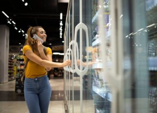 Fampe Delas viabiliza R$ 167,3 milhões em crédito para mulheres empreendedoras em Minas Gerais mulher-com-carrinho-de-compras-abrindo-geladeira-para-levar-comida-no-supermercado-enquanto-fala-ao-telefone
