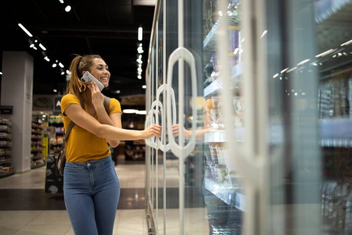 mulher-com-carrinho-de-compras-abrindo-geladeira-para-levar-comida-no-supermercado-enquanto-fala-ao-telefone (1) mulher-com-carrinho-de-compras-abrindo-geladeira-para-levar-comida-no-supermercado-enquanto-fala-ao-telefone